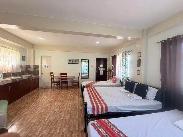 Larger room with three beds, a kitchenette and a dining table