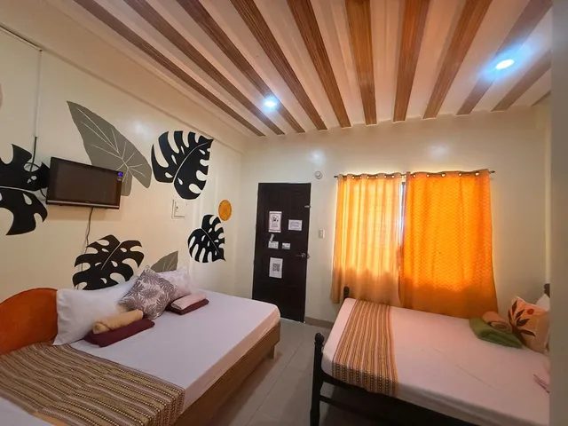 Room with two beds, tropical-leaf wall art and a wall-mounted TV