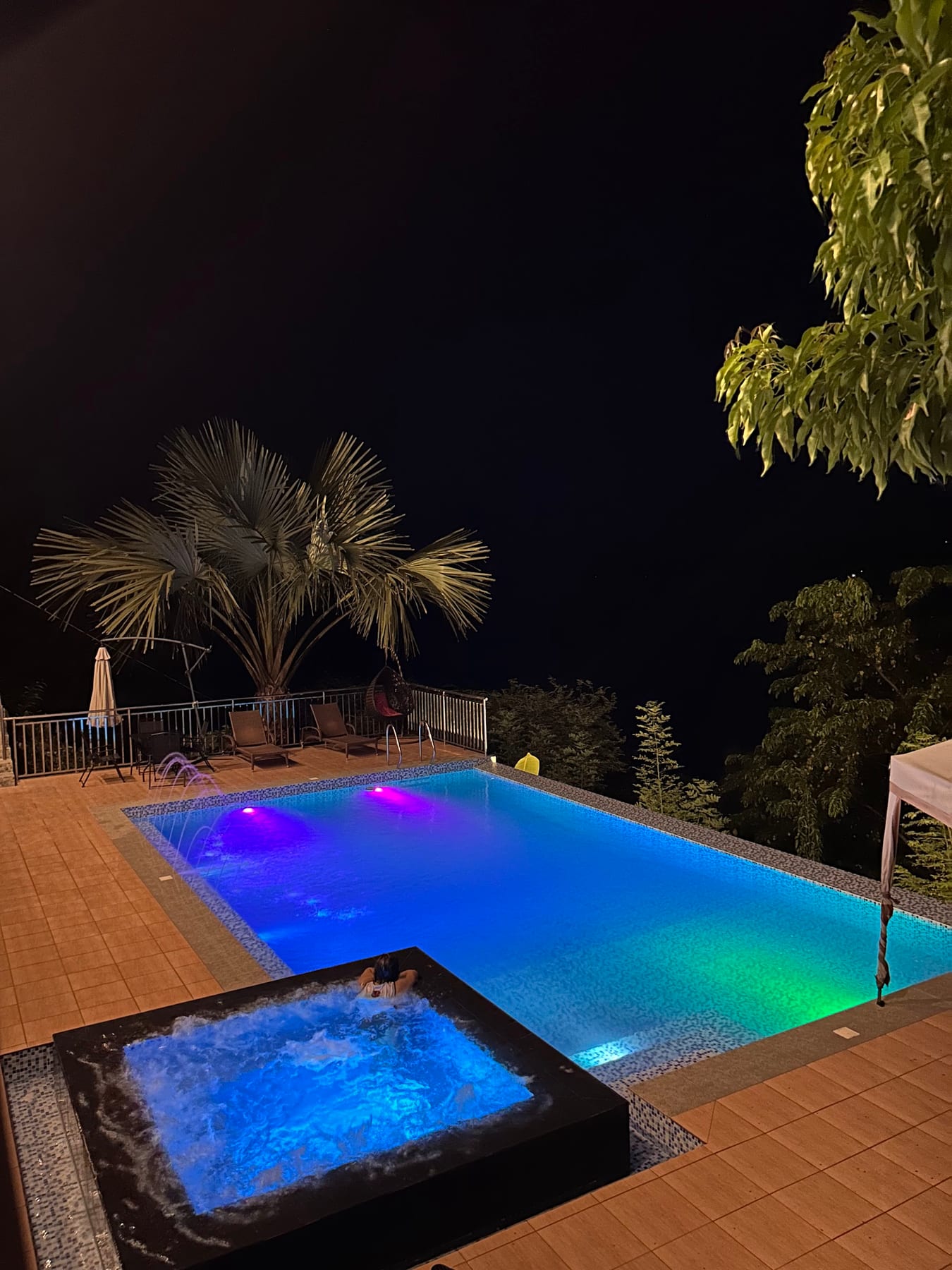 Guisian Cove Resort pool at night with colorful underwater lighting and a glowing jacuzzi
