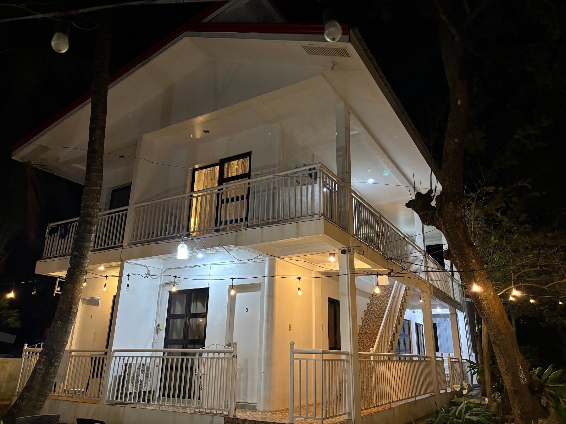 Two-storey casita exterior at night, lit by string lights, at Guisian Cove Resort